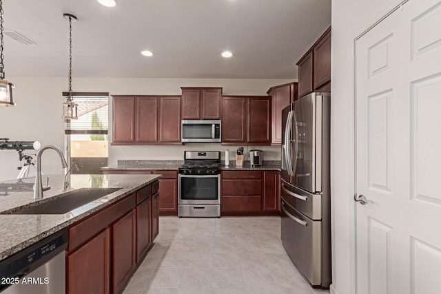 kitchen with light stone countertops, appliances with stainless steel finishes, sink, light tile patterned floors, and pendant lighting