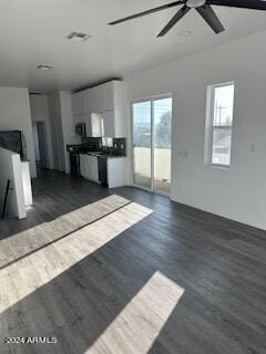 unfurnished living room with ceiling fan, a wealth of natural light, and dark hardwood / wood-style floors