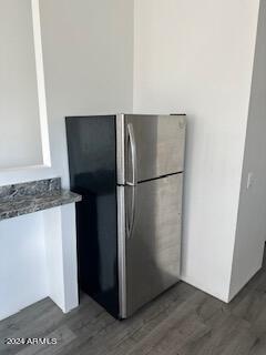 kitchen with stainless steel refrigerator, dark stone counters, and dark hardwood / wood-style floors