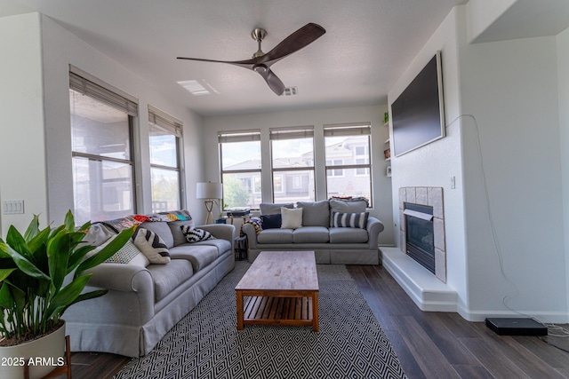 15221 N Clubgate Dr Unit 2132, Scottsdale, AZ 85254 - living area with dark wood-style flooring, a tiled fireplace, baseboards, visible vents, and ceiling fan
