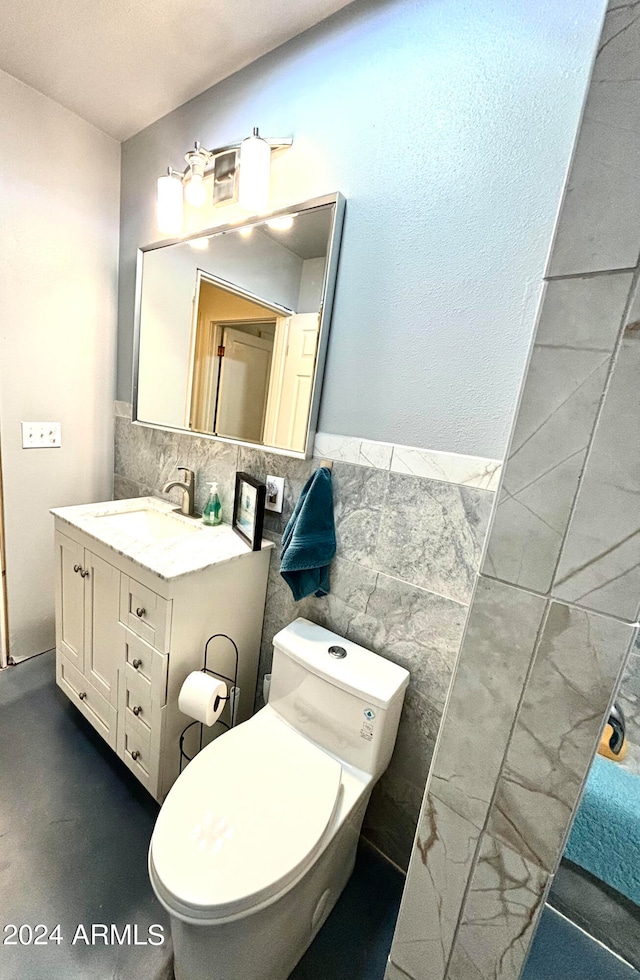 bathroom with tile walls, vanity, toilet, and tasteful backsplash