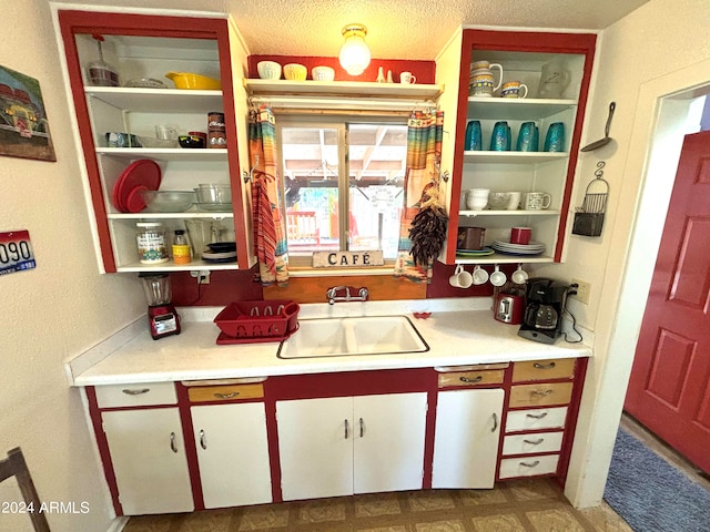 kitchen with white cabinets, a textured ceiling, and sink