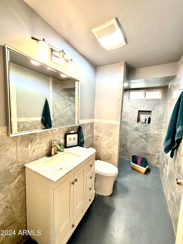 bathroom with tile walls, a textured ceiling, a shower, vanity, and toilet