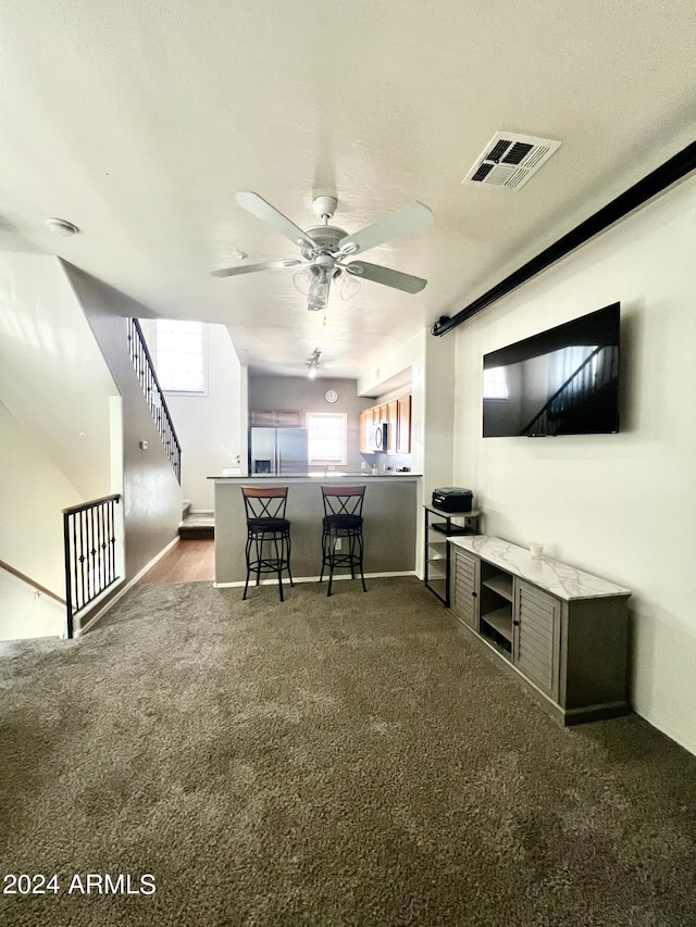 interior space featuring ceiling fan and dark carpet