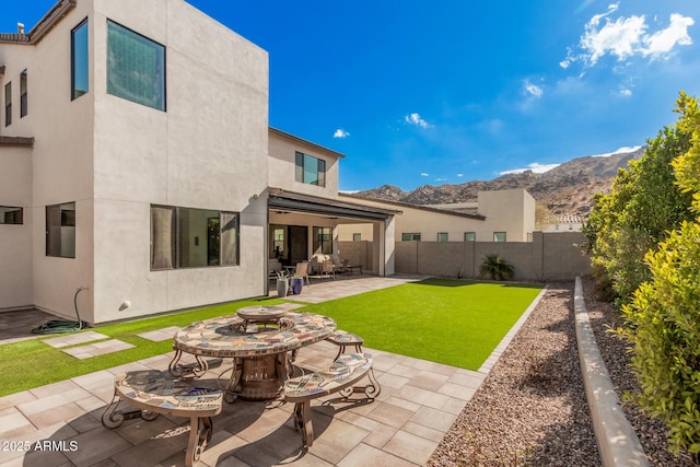 back of property featuring a mountain view, a lawn, and a patio area