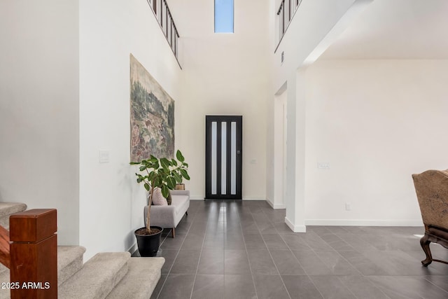 entryway with a towering ceiling and tile patterned flooring