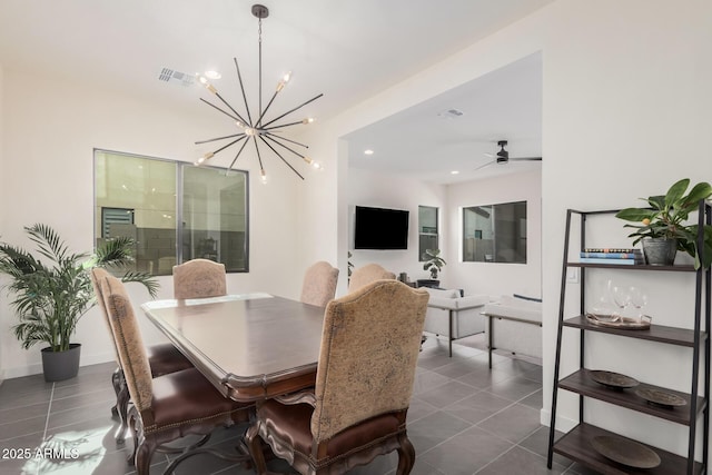 dining room with ceiling fan with notable chandelier and dark tile patterned flooring