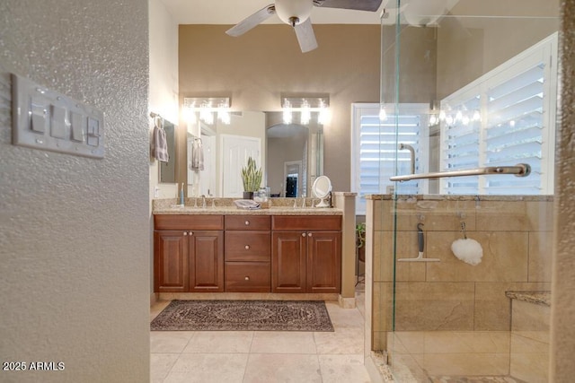 bathroom with tile patterned flooring, vanity, a shower with door, and ceiling fan