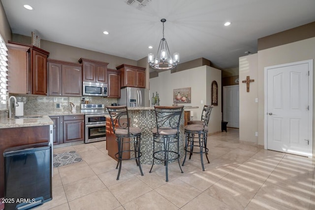 kitchen featuring sink, a center island, stainless steel appliances, light stone countertops, and backsplash