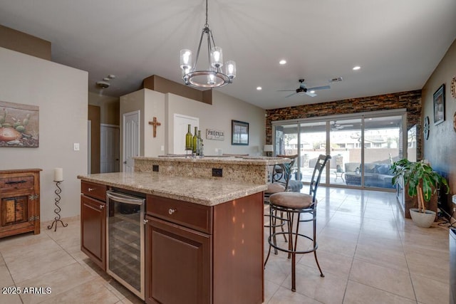 kitchen with light tile patterned flooring, pendant lighting, wine cooler, a kitchen breakfast bar, and a center island