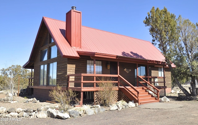 view of front facade featuring a chimney, a porch, and metal roof