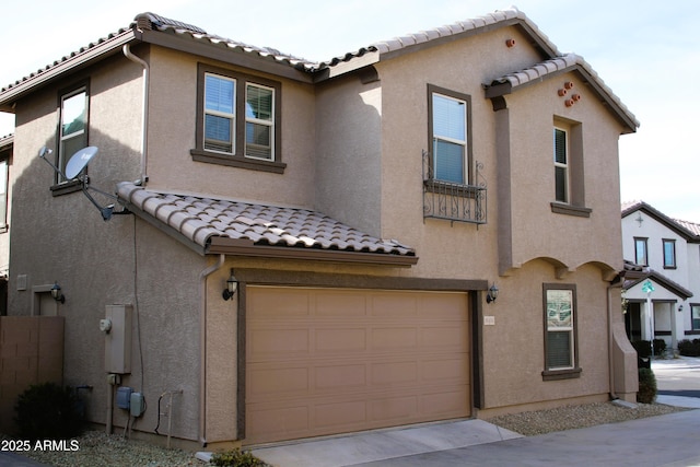 mediterranean / spanish house with a garage, a tile roof, driveway, and stucco siding