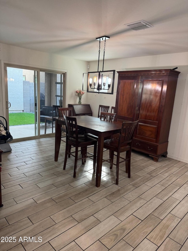 dining area featuring visible vents, an inviting chandelier, and light wood-style floors