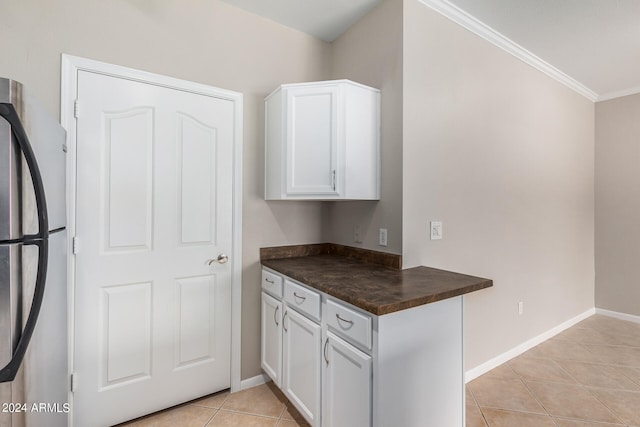 kitchen featuring white cabinets, light tile patterned flooring, crown molding, and stainless steel refrigerator