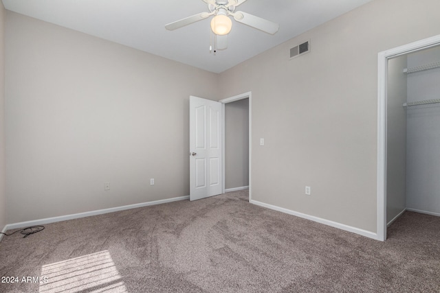 unfurnished bedroom featuring a walk in closet, ceiling fan, a closet, and carpet