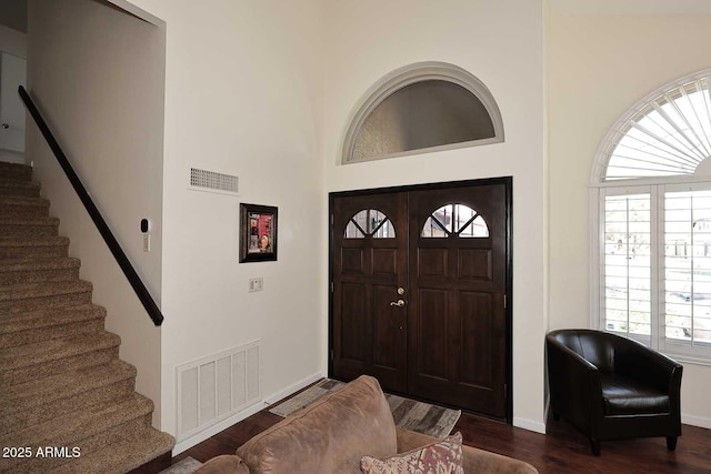 foyer with dark wood-style flooring, visible vents, baseboards, and stairs