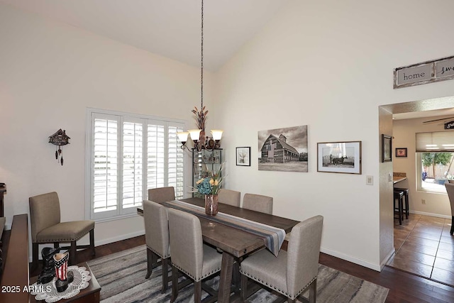 dining room featuring a chandelier, dark wood-type flooring, high vaulted ceiling, and baseboards