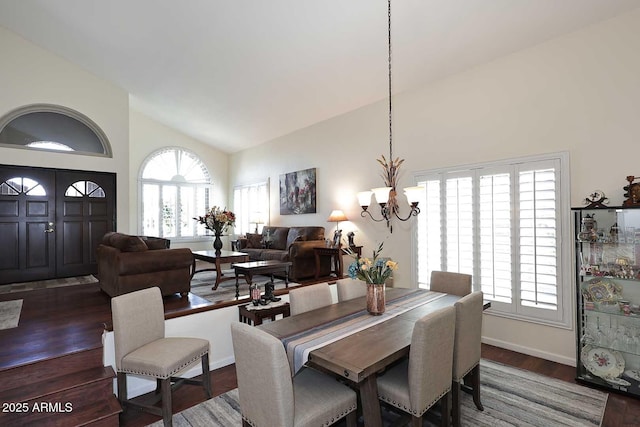 dining room featuring high vaulted ceiling, plenty of natural light, dark wood finished floors, and a notable chandelier