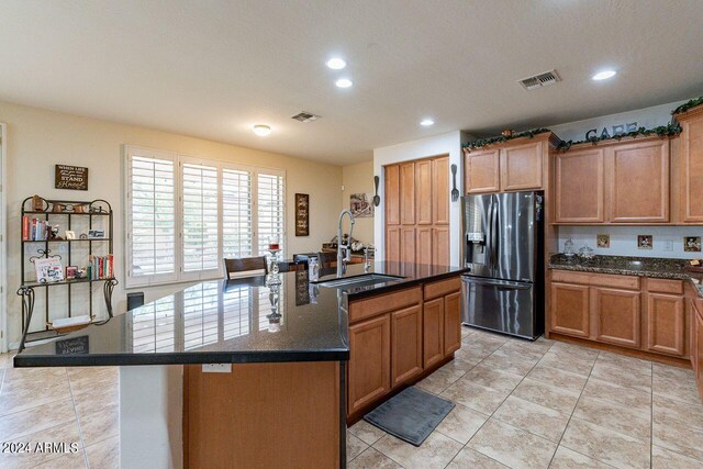 kitchen with an island with sink, sink, light tile patterned floors, and stainless steel fridge with ice dispenser