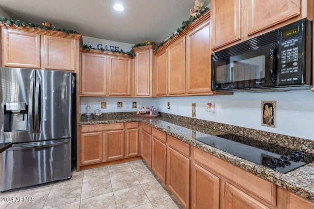 kitchen with black appliances, light tile patterned floors, and dark stone counters