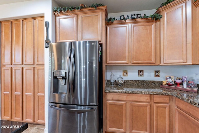 kitchen featuring stainless steel fridge with ice dispenser and dark stone counters