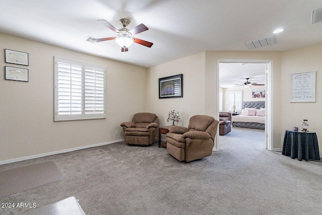 living area featuring light colored carpet and ceiling fan