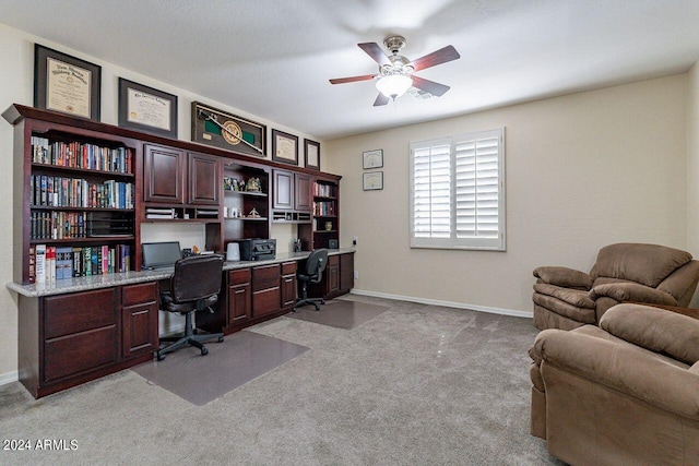 office area with built in desk, ceiling fan, and light carpet