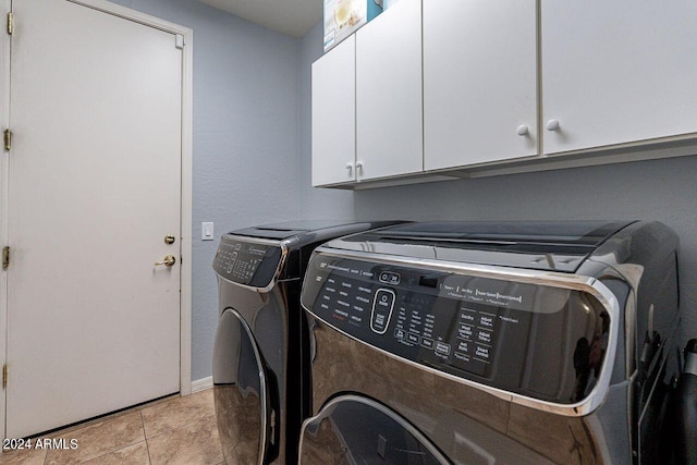 laundry room featuring cabinets, washing machine and dryer, and light tile patterned floors