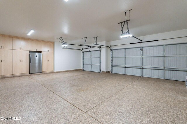 garage featuring stainless steel fridge and a garage door opener