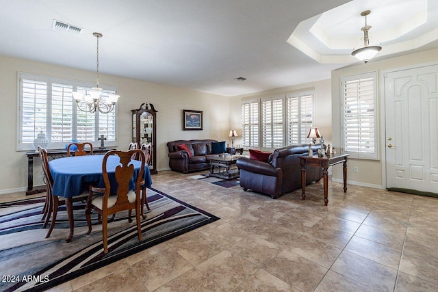 dining area featuring a tray ceiling and an inviting chandelier