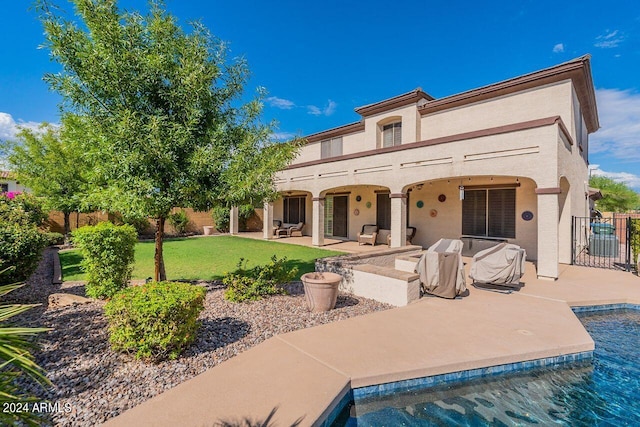 back of property with a fenced in pool, a yard, and a patio