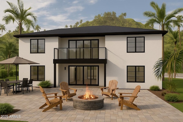 back of house with a balcony, a fire pit, stucco siding, and a patio
