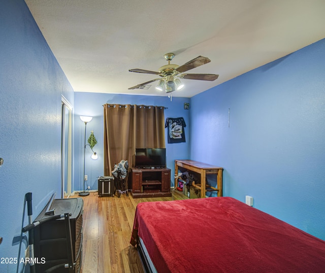 703 N Redwood Ln, Buckeye, AZ 85326 - bedroom featuring wood finished floors, a textured wall, and a ceiling fan