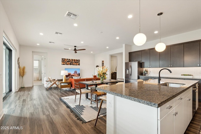 kitchen with sink, an island with sink, white cabinets, stainless steel fridge with ice dispenser, and decorative light fixtures