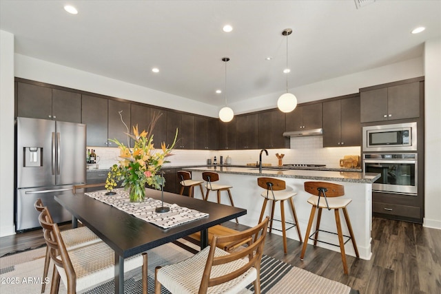 kitchen featuring dark brown cabinetry, tasteful backsplash, dark hardwood / wood-style floors, and appliances with stainless steel finishes