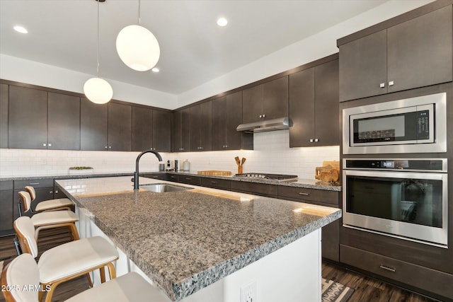 kitchen with pendant lighting, sink, backsplash, stainless steel appliances, and dark brown cabinets