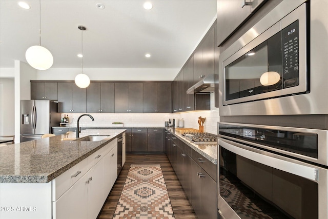 kitchen with pendant lighting, appliances with stainless steel finishes, sink, and backsplash