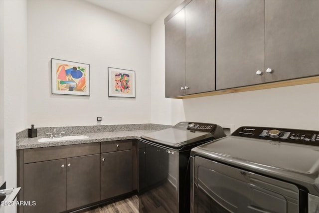 washroom with dark wood-type flooring, cabinets, washer and clothes dryer, and sink