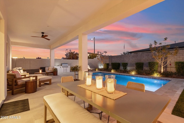 pool at dusk with area for grilling, a patio area, and ceiling fan