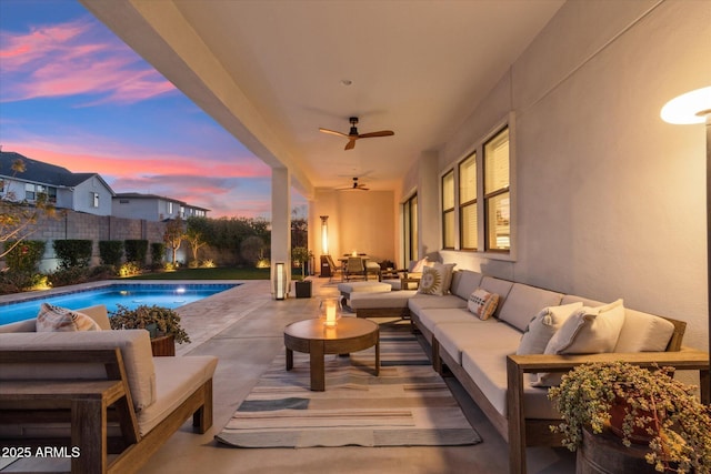 pool at dusk with an outdoor living space, a patio, and ceiling fan