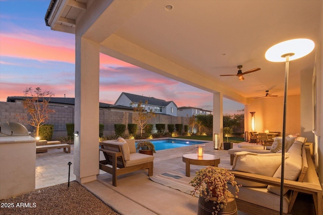 pool at dusk with an outdoor living space, area for grilling, ceiling fan, and a patio area