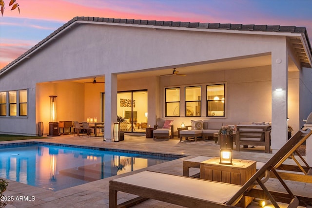 back house at dusk with an outdoor living space with a fire pit, a patio, and ceiling fan