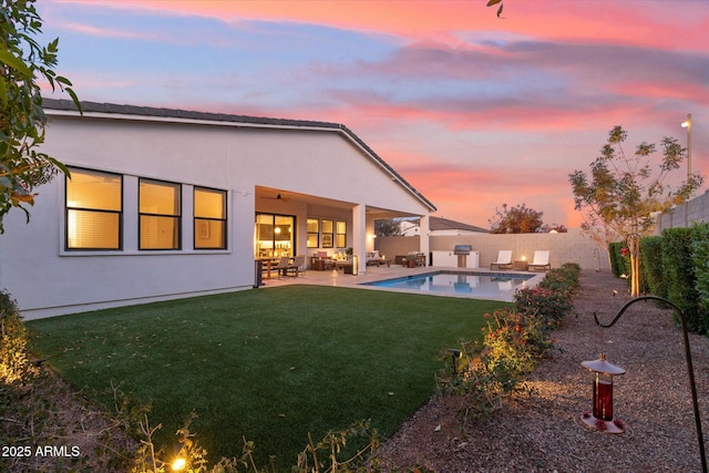 back house at dusk featuring a fenced in pool, a lawn, and a patio