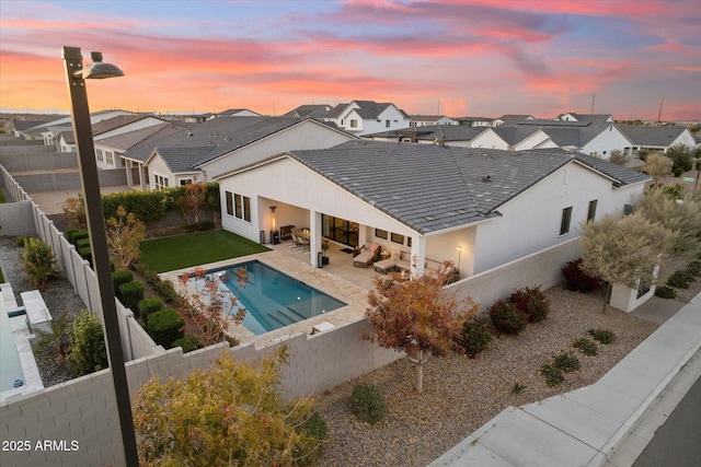 pool at dusk featuring a patio area and outdoor lounge area