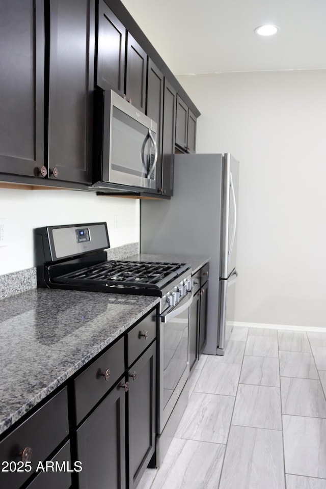 kitchen featuring dark stone countertops, recessed lighting, baseboards, and stainless steel appliances