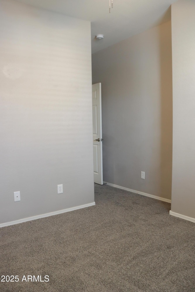 empty room featuring baseboards and dark colored carpet