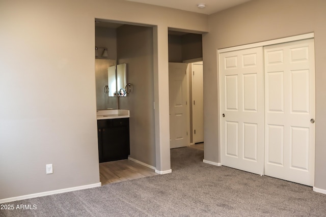 unfurnished bedroom featuring a closet, baseboards, carpet, and ensuite bathroom