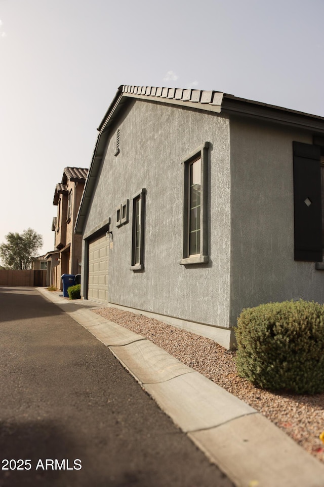 view of side of property featuring a garage, driveway, and stucco siding