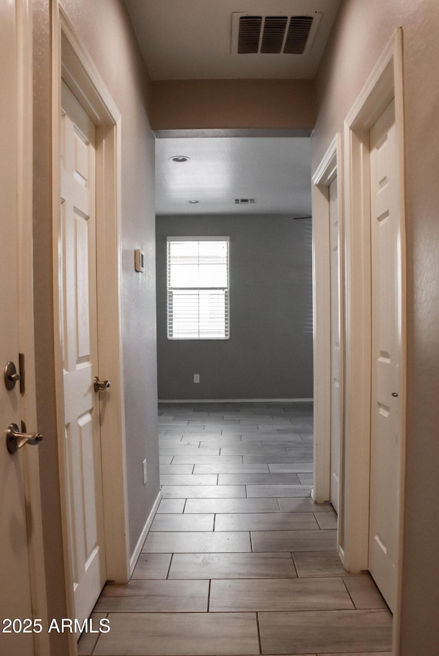 hallway featuring visible vents, baseboards, and wood tiled floor