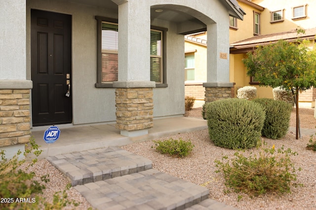 property entrance featuring stone siding and stucco siding